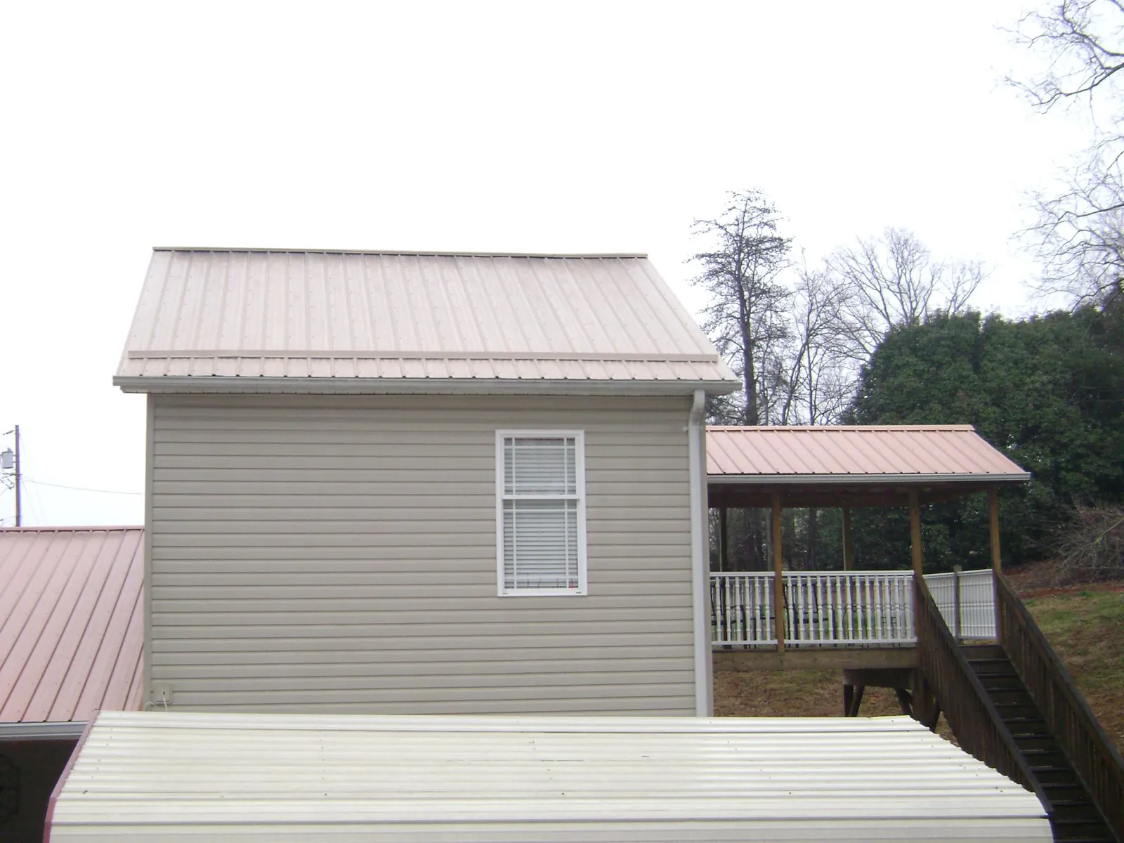 Tan metal roofs on a two story addition and attached porch, from a Roof Replacement job in Fulton